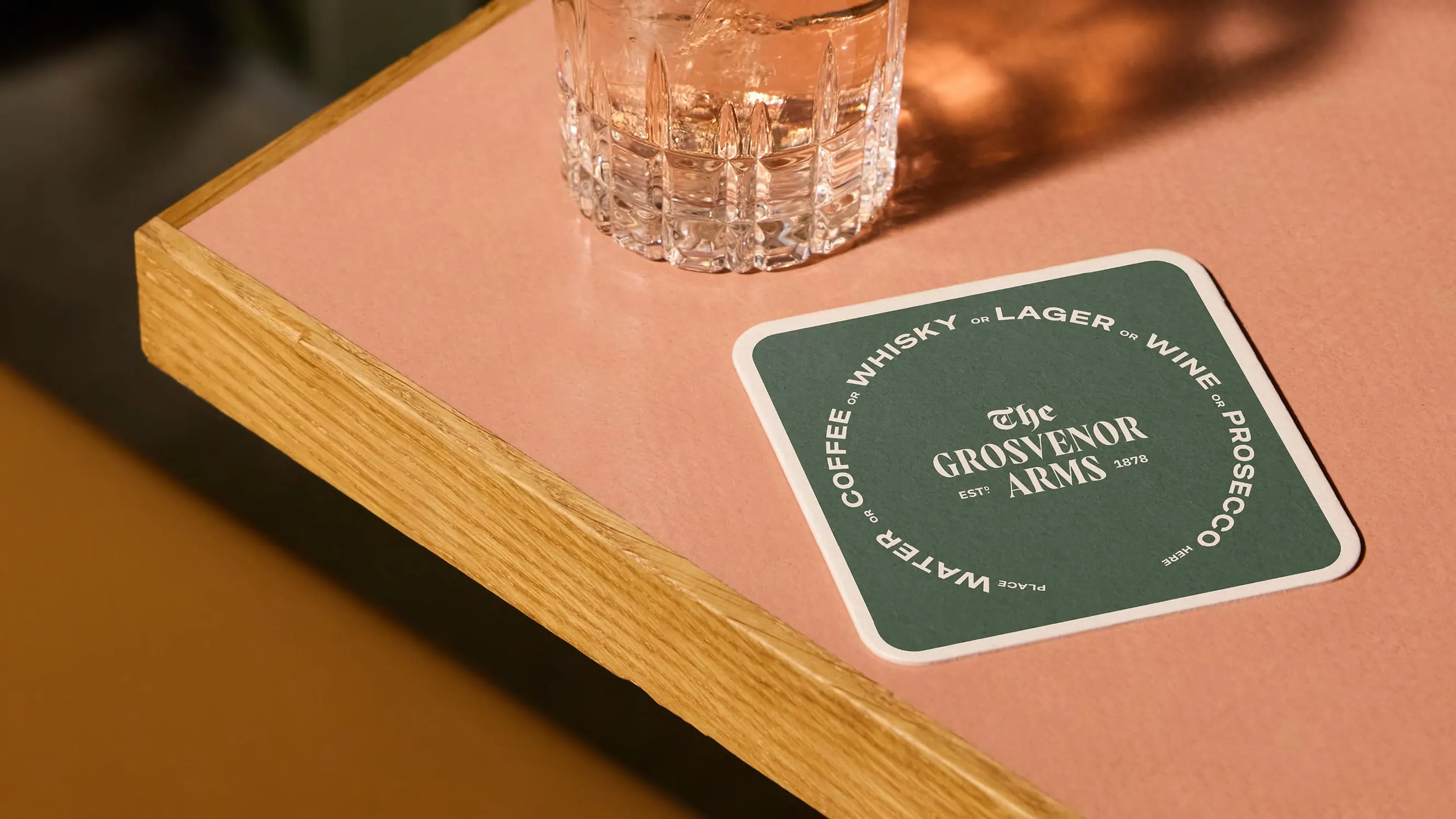 A Grosvenor Arms beer mat reading "water or coffee or whisky or lager or wine or prosecco"