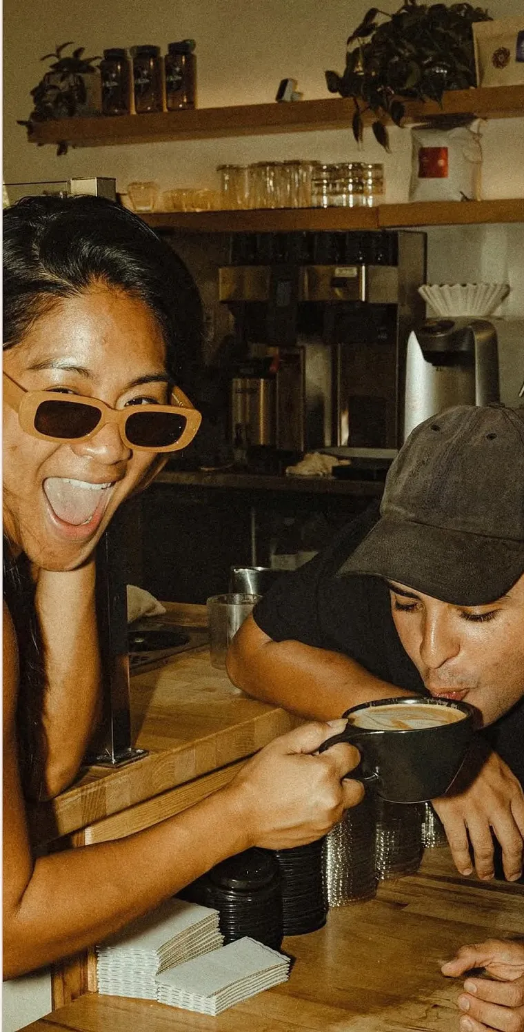 Two guests at the coffee counter, one drinking a flat white
