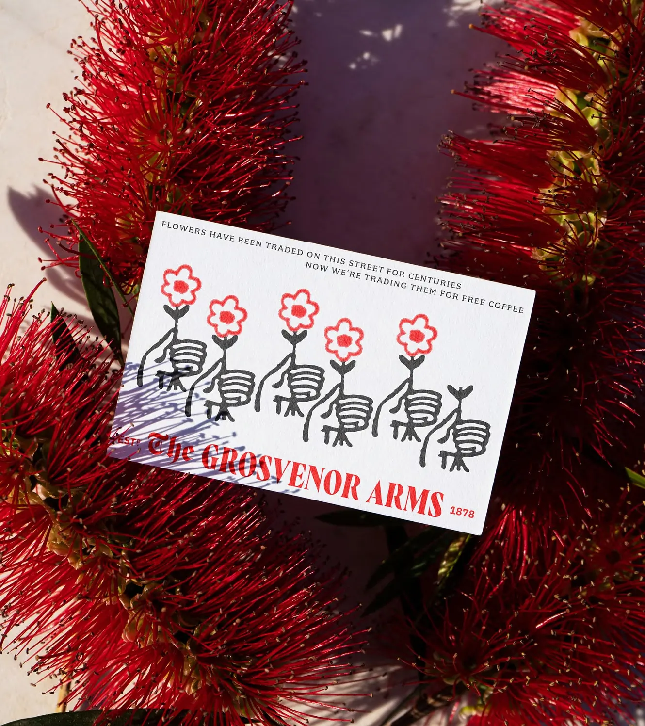 A card reading "flowers have been traded on this street for centuries" among red flowers