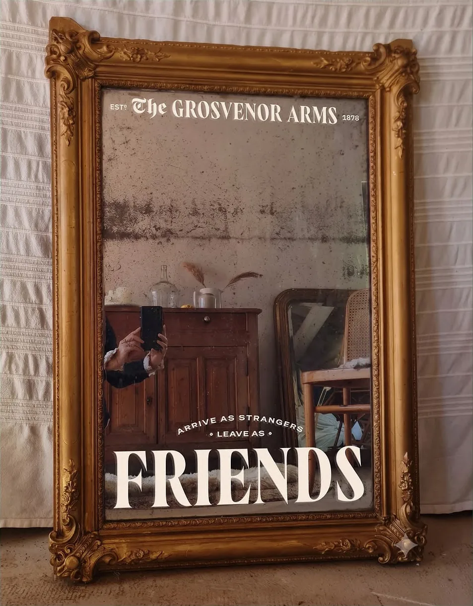 A framed mirror reading 'arrive as strangers, leave as friends'